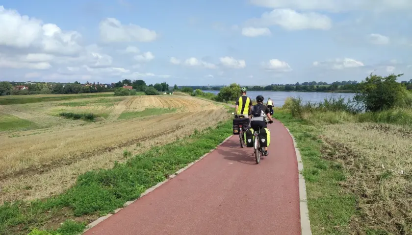 Rowerzyści na tczewskiej trasie podziwiają krajobraz z polami i rzeką.