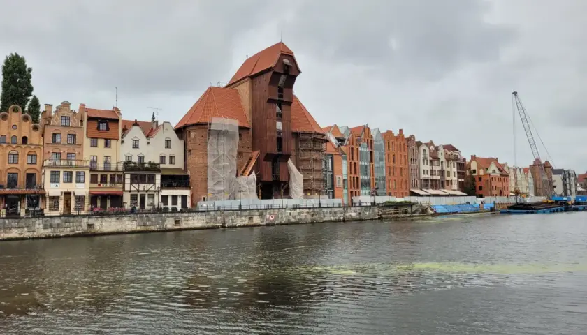 Gdańsk Żuraw, zabytkowy dźwig portowy, góruje nad malowniczą nadbrzeżną zabudową.