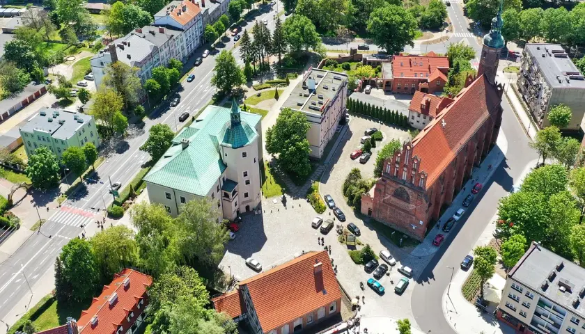 Słupsk atrakcje: zamek Książąt Pomorskich z zielonym dachem i ceglany kościół z wieżą.