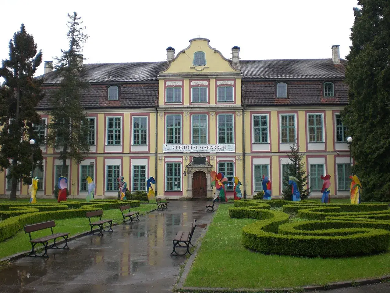 Pałac Opatów w Oliwie, otoczony zielenią i kolorowymi rzeźbami, zaprasza do zwiedzania.