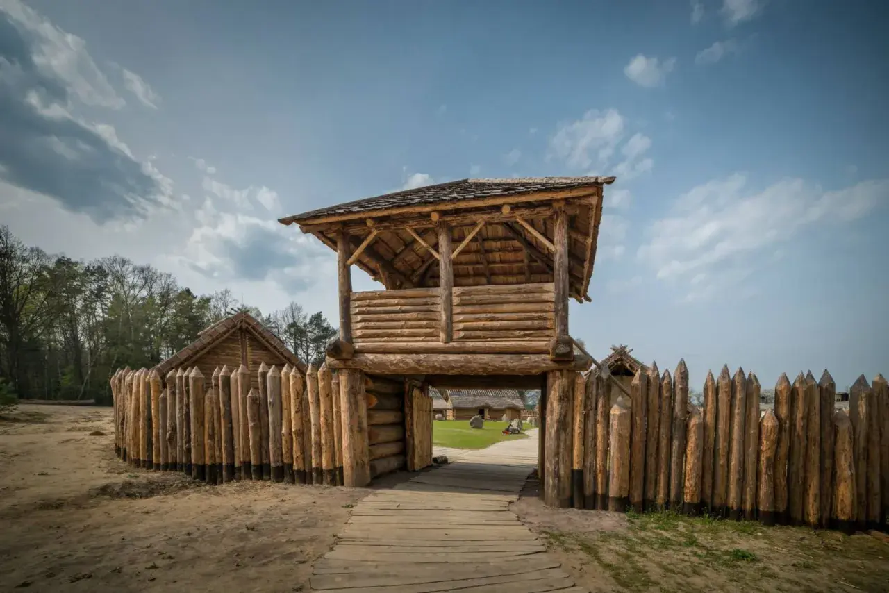 Drewniana wieża strażnicza i palisada. W oddali widać chaty. Sławutowo atrakcje przenoszą w czasy dawnych Słowian.