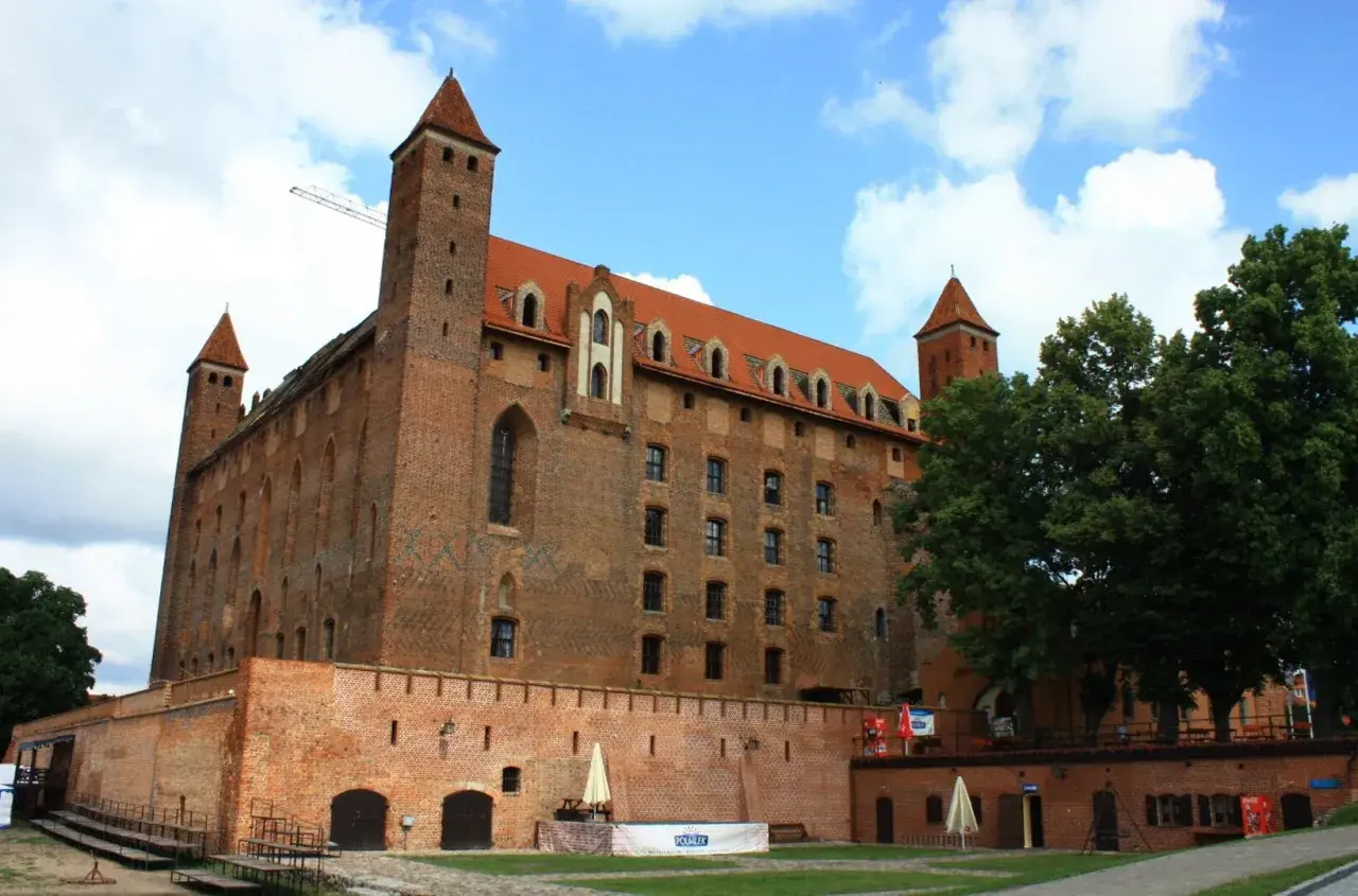 Gotycki zamek, duma kociewie miasta, z czerwonej cegły, z wieżami i czerwonym dachem, pod błękitnym niebem.