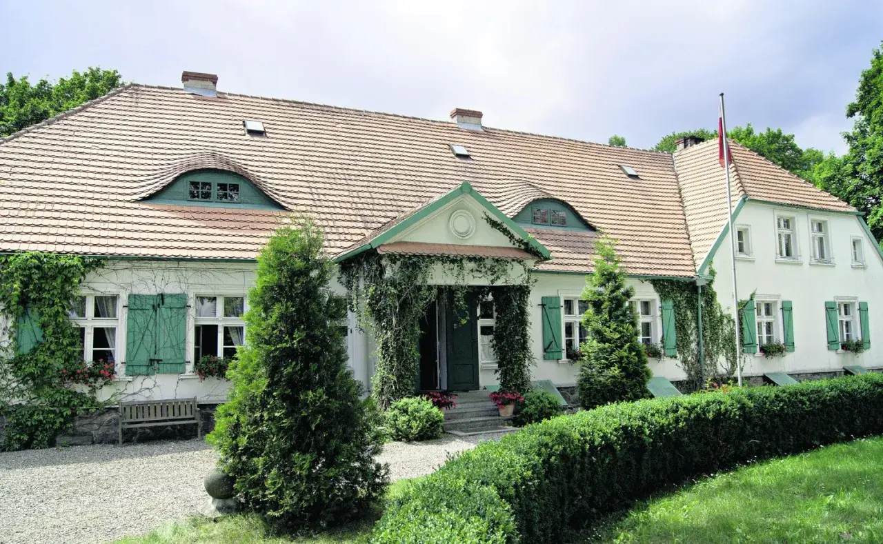 Urokliwy sikorzyno dworek z zielonymi okiennicami i pnączami.