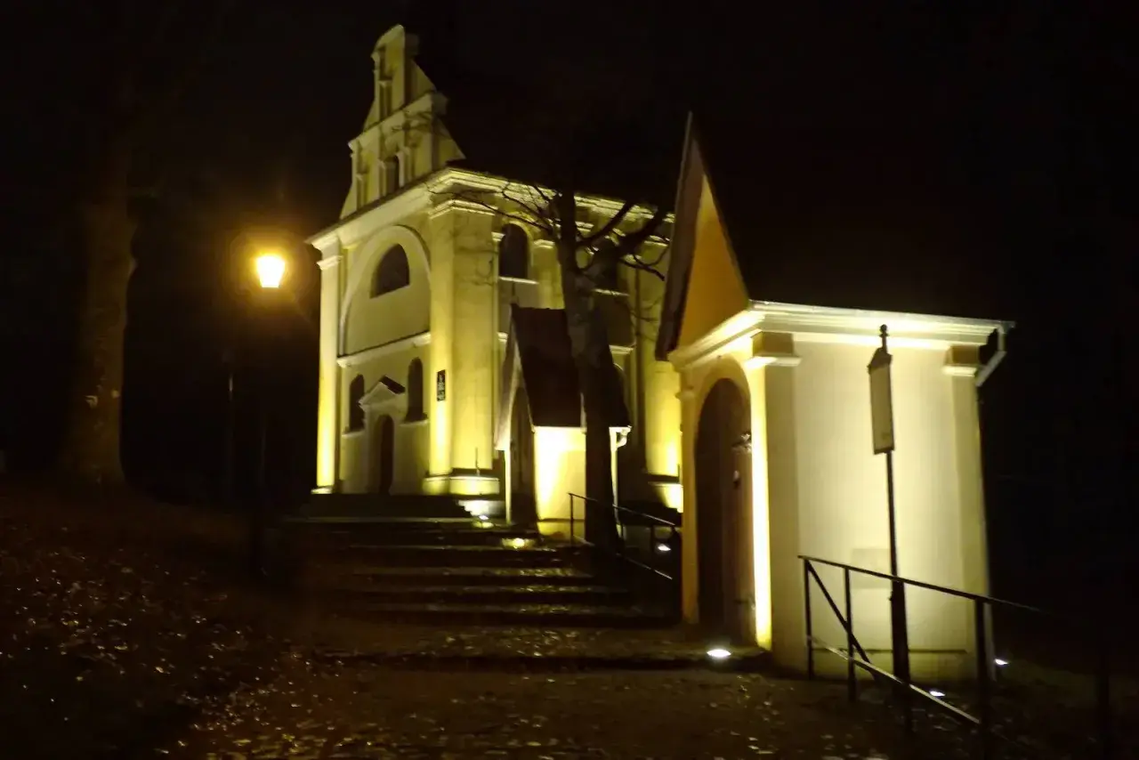 Nocne iluminacje kościołów w Wejherowie. Schody prowadzą do zabytkowych budowli, oświetlonych ciepłym światłem.