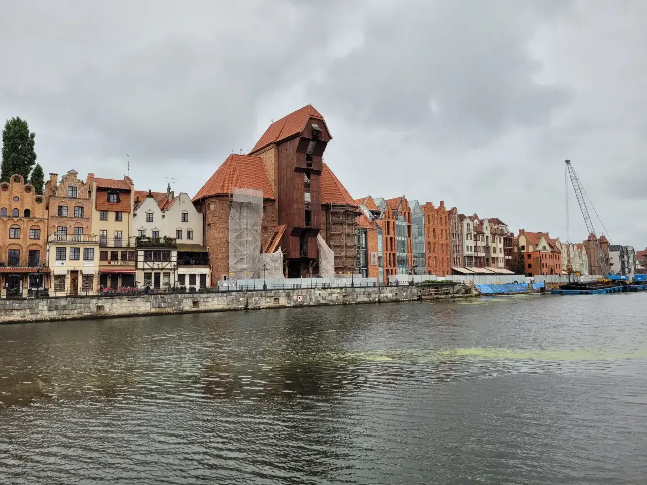 Gdańsk Żuraw, zabytkowy dźwig portowy, góruje nad malowniczą nadbrzeżną zabudową.