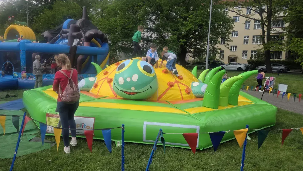 Dzieci bawią się na dmuchanym placu zabaw w kształcie gąsienicy. To świetne **nowęcin atrakcje** dla najmłodszych.