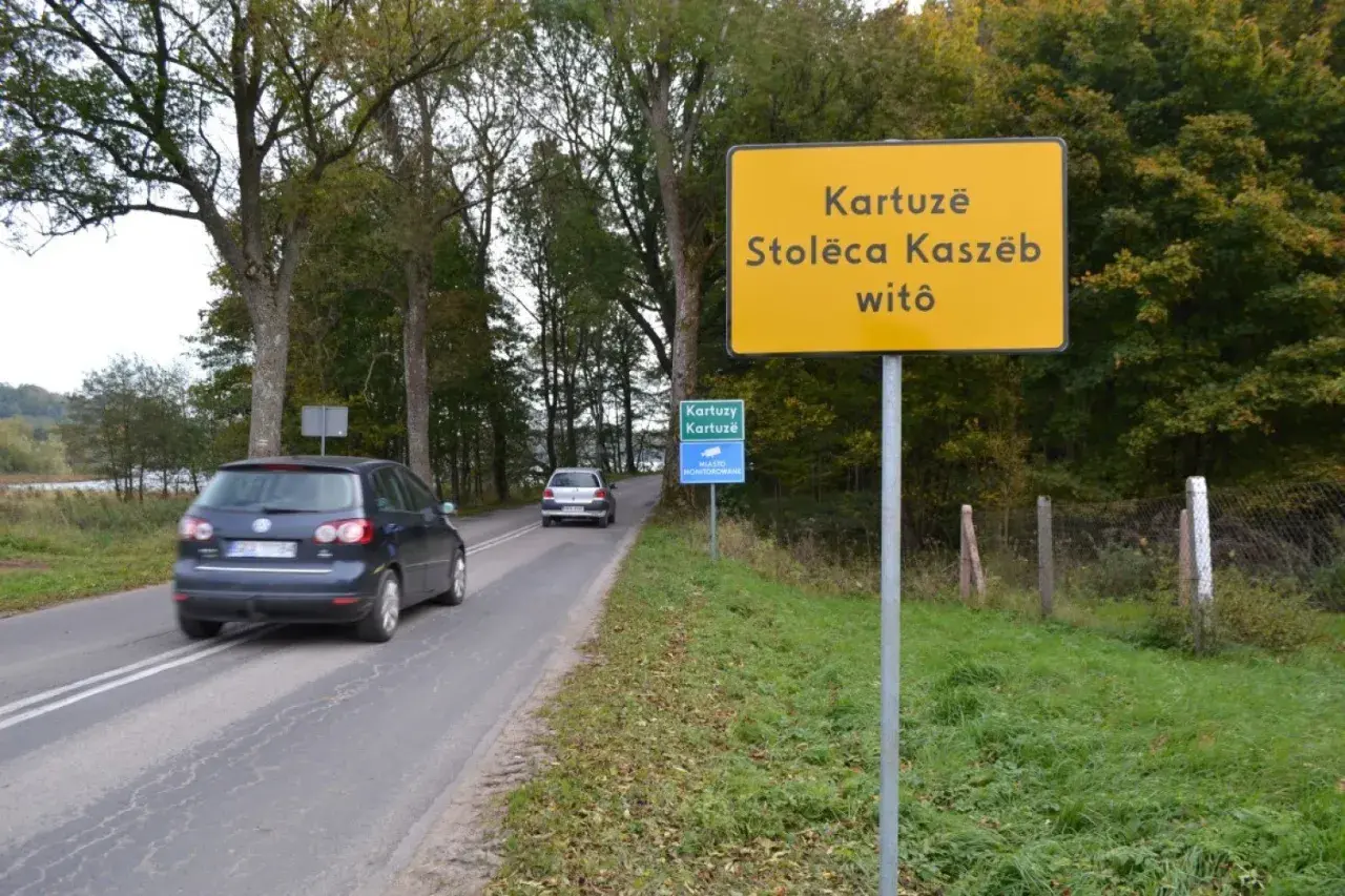 Żółty znak informuje: Kartuzë, Stolëca Kaszëb witô. Droga prowadzi do stolicy Kaszub.