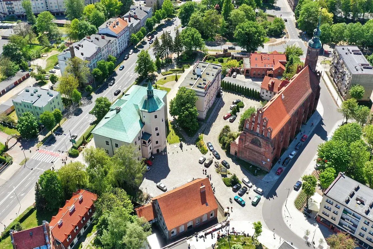 Słupsk atrakcje: zamek Książąt Pomorskich z zielonym dachem i ceglany kościół z wieżą.