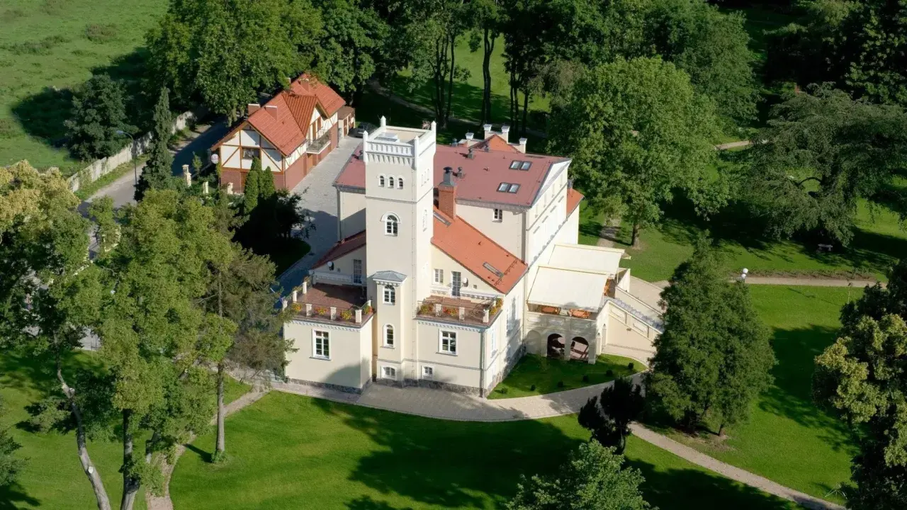 Dworek z wieżą otoczony zielenią, idealne romantyczne miejsce na Kaszubach.
