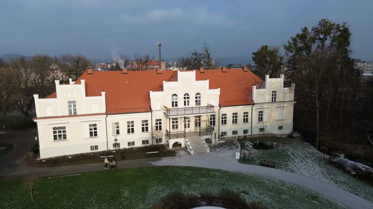 Pałac Przebendowskich w Wejherowie, z charakterystycznym czerwonym dachem i jasną fasadą, otoczony parkiem.