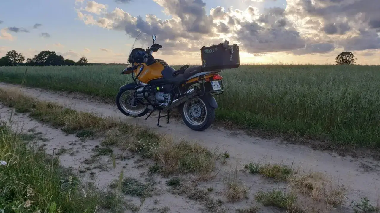 Żółty motocykl turystyczny na drodze polnej wśród pól zboża. Zachód słońca na Kaszubach, idealny na wyprawę motocyklem.