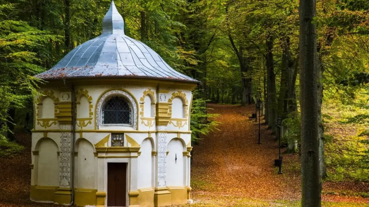 Kaplica kalwarii wejherowo w jesiennej scenerii, otoczona drzewami i ścieżką usłaną liśćmi.