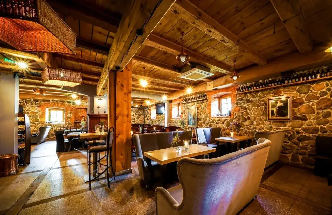 Przytulne wnętrze restauracji z kamiennymi ścianami i drewnianym sufitem. Idealne miejsce na spotkanie, jakbyś był w nordowi mol.