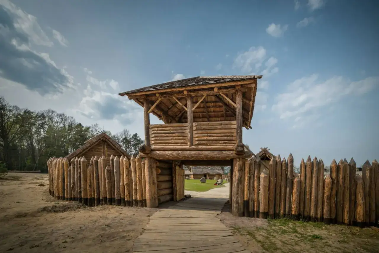 Drewniana wieża strażnicza i palisada. W oddali widać chaty. Sławutowo atrakcje przenoszą w czasy dawnych Słowian.