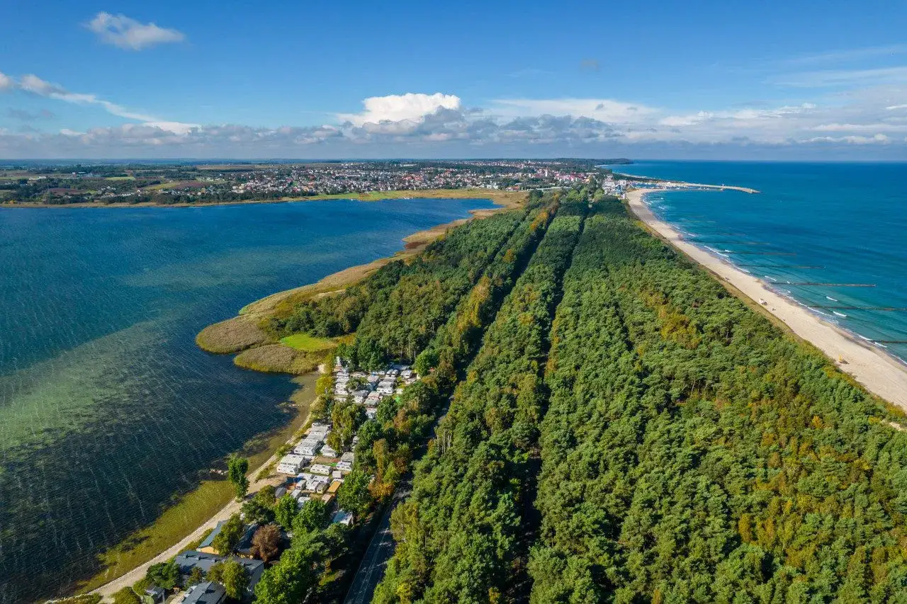 Półwysep Helski widziany z lotu ptaka: las sosnowy, plaża, morze i zatoka. Widać też camping i zabudowania.